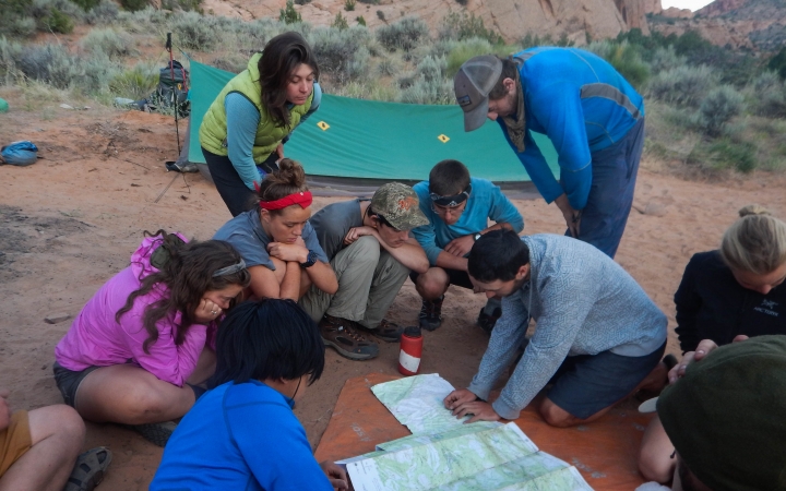 a group of students examine a map that is spread out on the ground